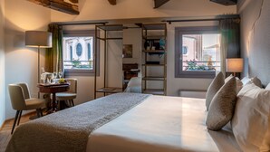 Ein Hotelzimmer mit einem großen Bett, einem Schreibtisch mit Lampe und Blick ins Freie.