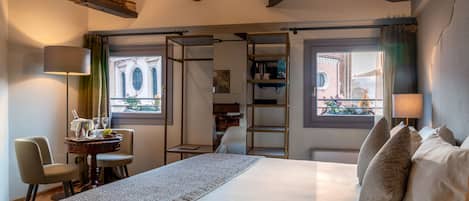 A hotel room with a large bed, a desk with a lamp, and a view of the outside.