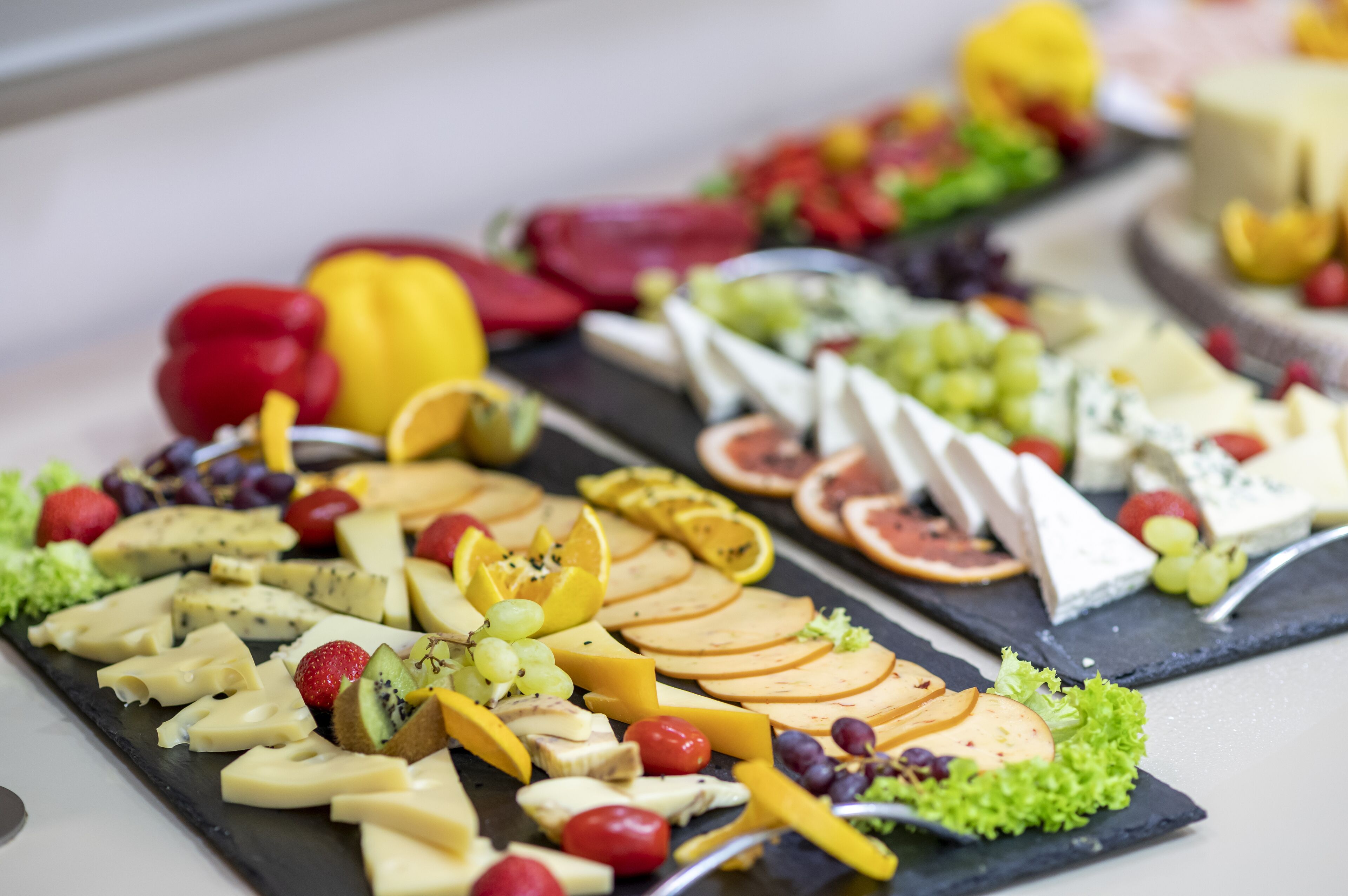 A variety of cheeses and fruits on a slate board.