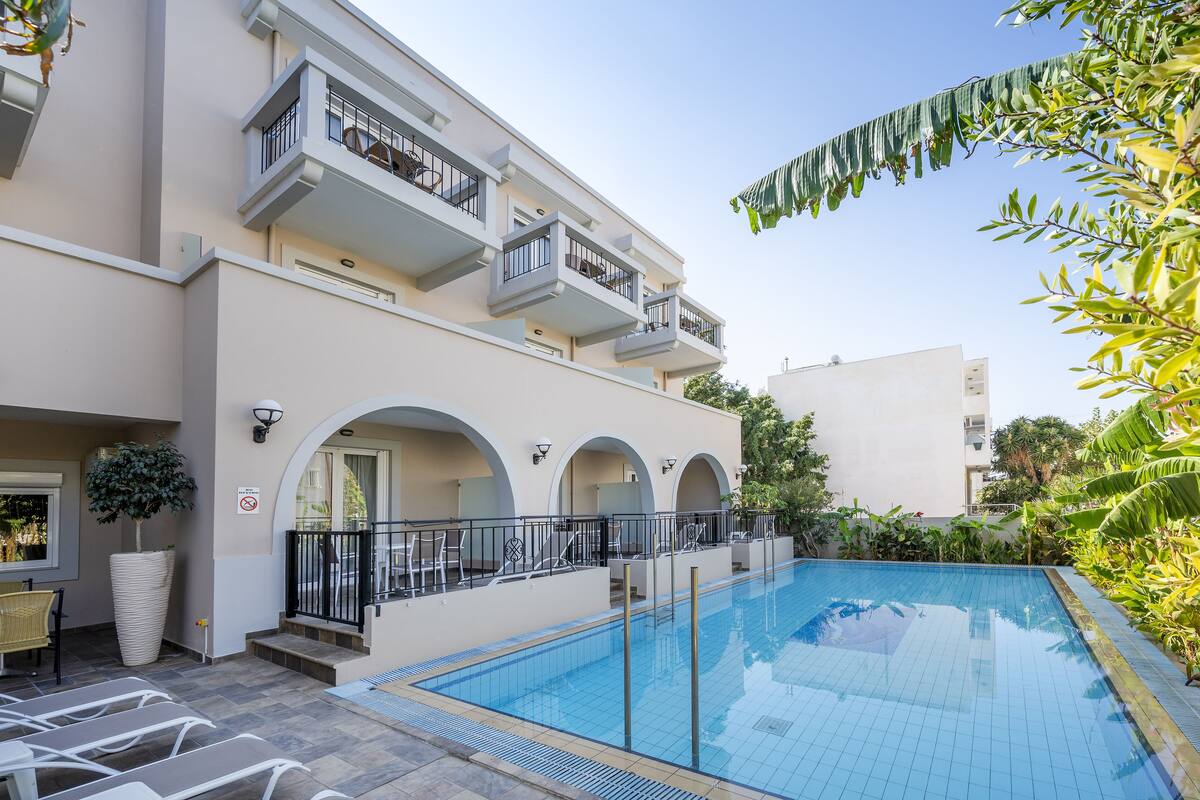 A modern hotel with a swimming pool, outdoor seating, and a balcony with a view.