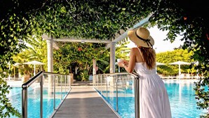 A poolside area with a glass balustrade, a covered walkway, and lounge chairs. - Peridis Family Resort (Kos)