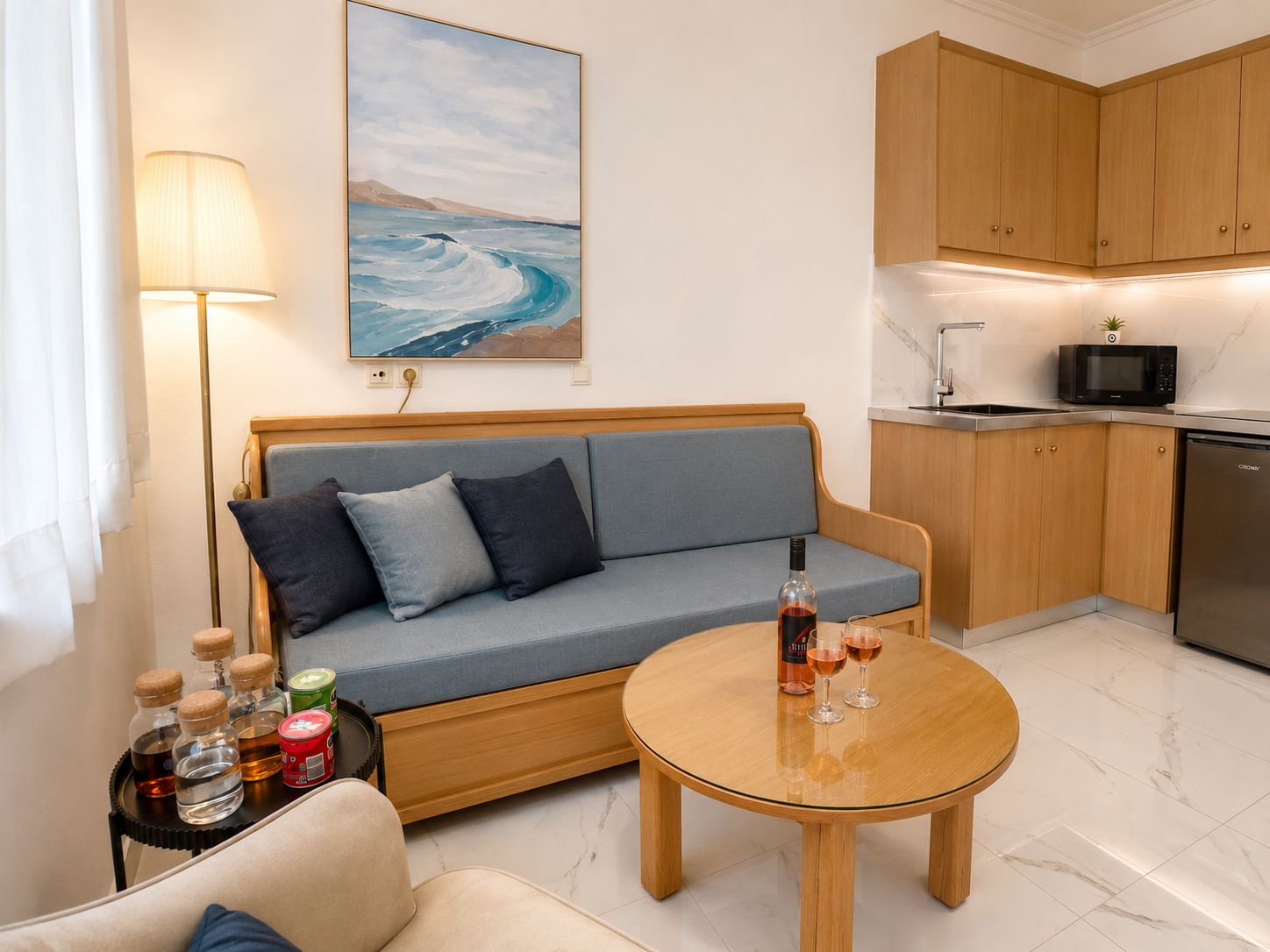 A modern living room with a sofa, a round coffee table, and a kitchen area with cabinets and appliances.