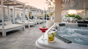 Un área de piscina en la azotea con sillones de descanso y un jacuzzi.