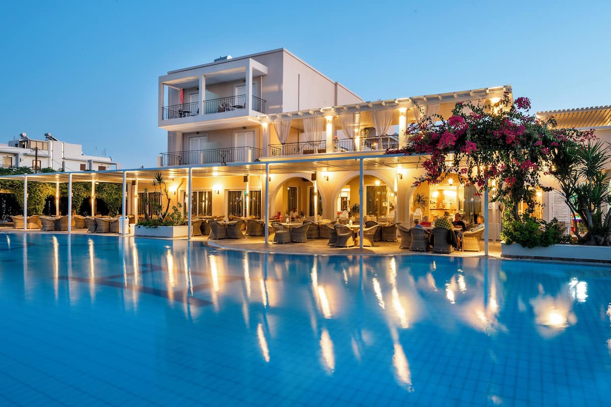 A hotel with a swimming pool, outdoor seating, and a balcony with flowers.