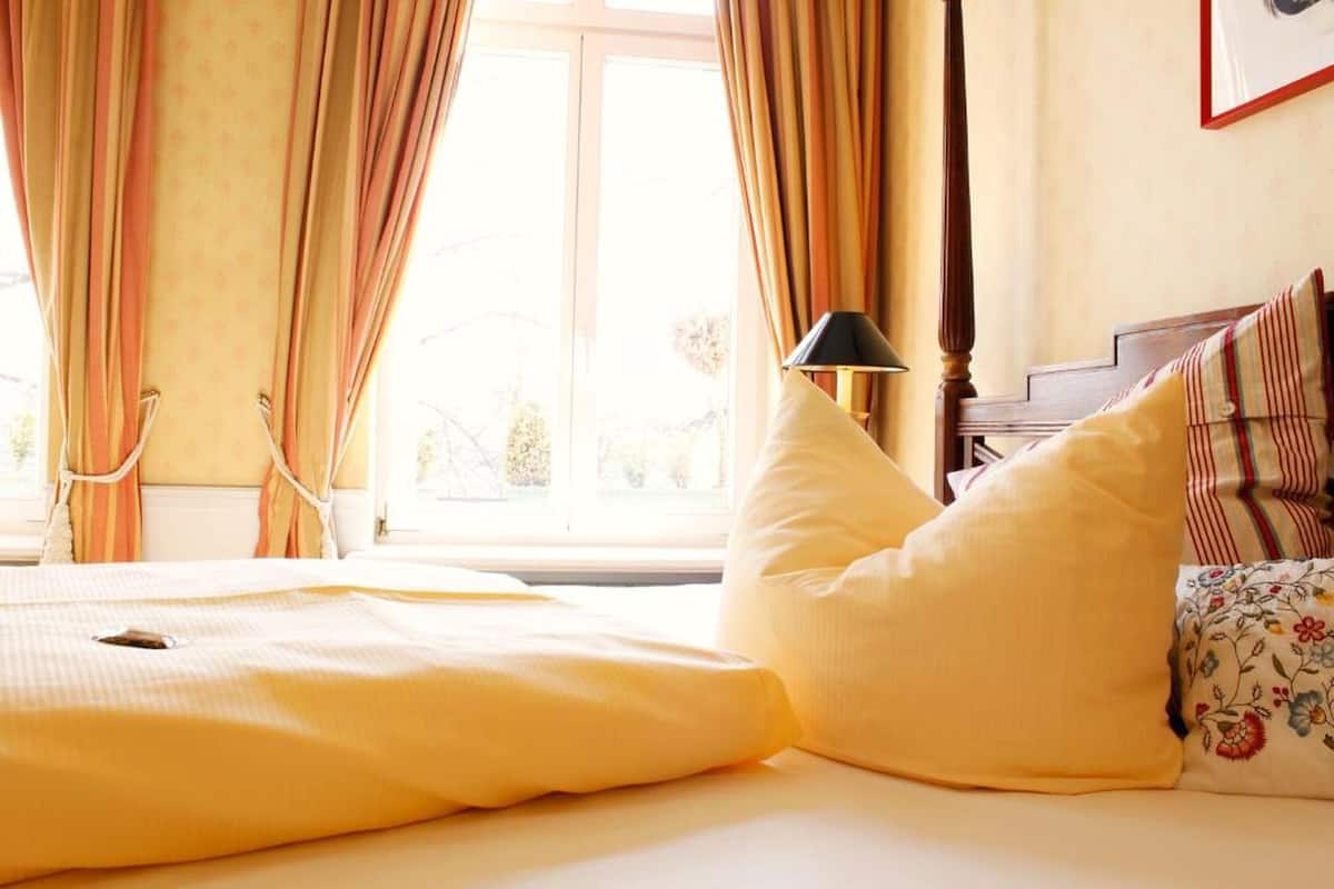 Une chambre à coucher avec un lit, des coussins jaunes, une lampe et des rideaux.