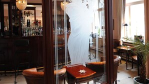 A bar area with a large mirror reflecting a statue, wooden furniture, and a potted plant. - Hotel Niederländischer Hof Schwerin (Schwerin)