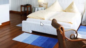 A bedroom with a bed, a nightstand, a lamp, a sailboat decoration, and a chair. - Hotel Niederländischer Hof Schwerin (Schwerin)
