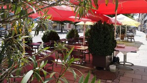 An outdoor café with red umbrellas, tables, and chairs. - Hotel Lehmeier (Neumarkt in der Oberpfalz)