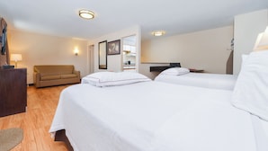 Habitación de hotel con dos camas, un sofá, un escritorio y un televisor.