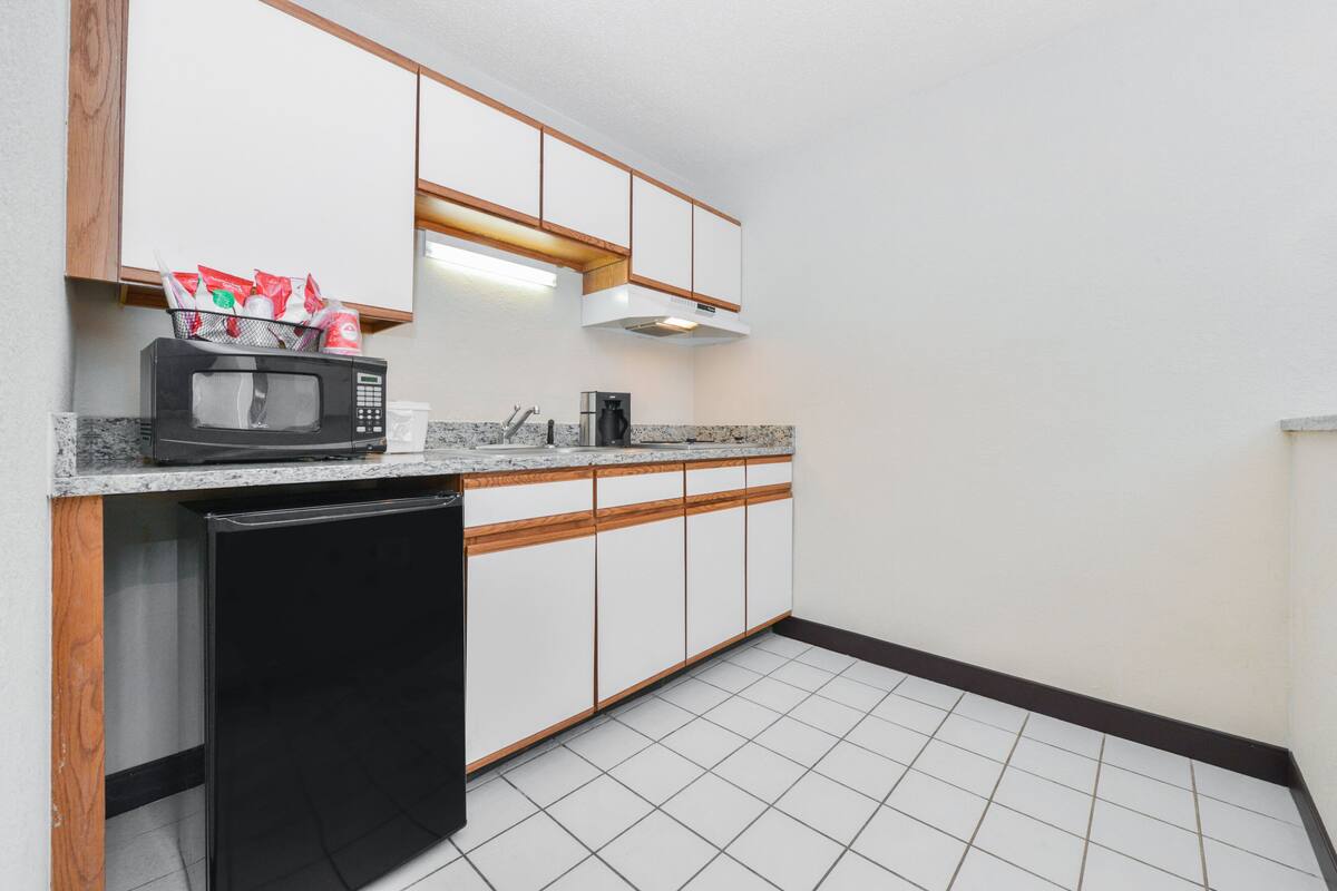 Una cocina compacta con microondas, cafetera y lavavajillas negro.
