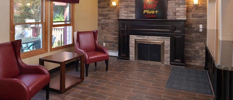 Una habitación con chimenea, dos sillones de cuero, una mesita y un cartel sobre la chimenea.