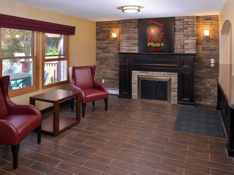 A room with a fireplace, two leather chairs, a small table, and a sign above the fireplace.