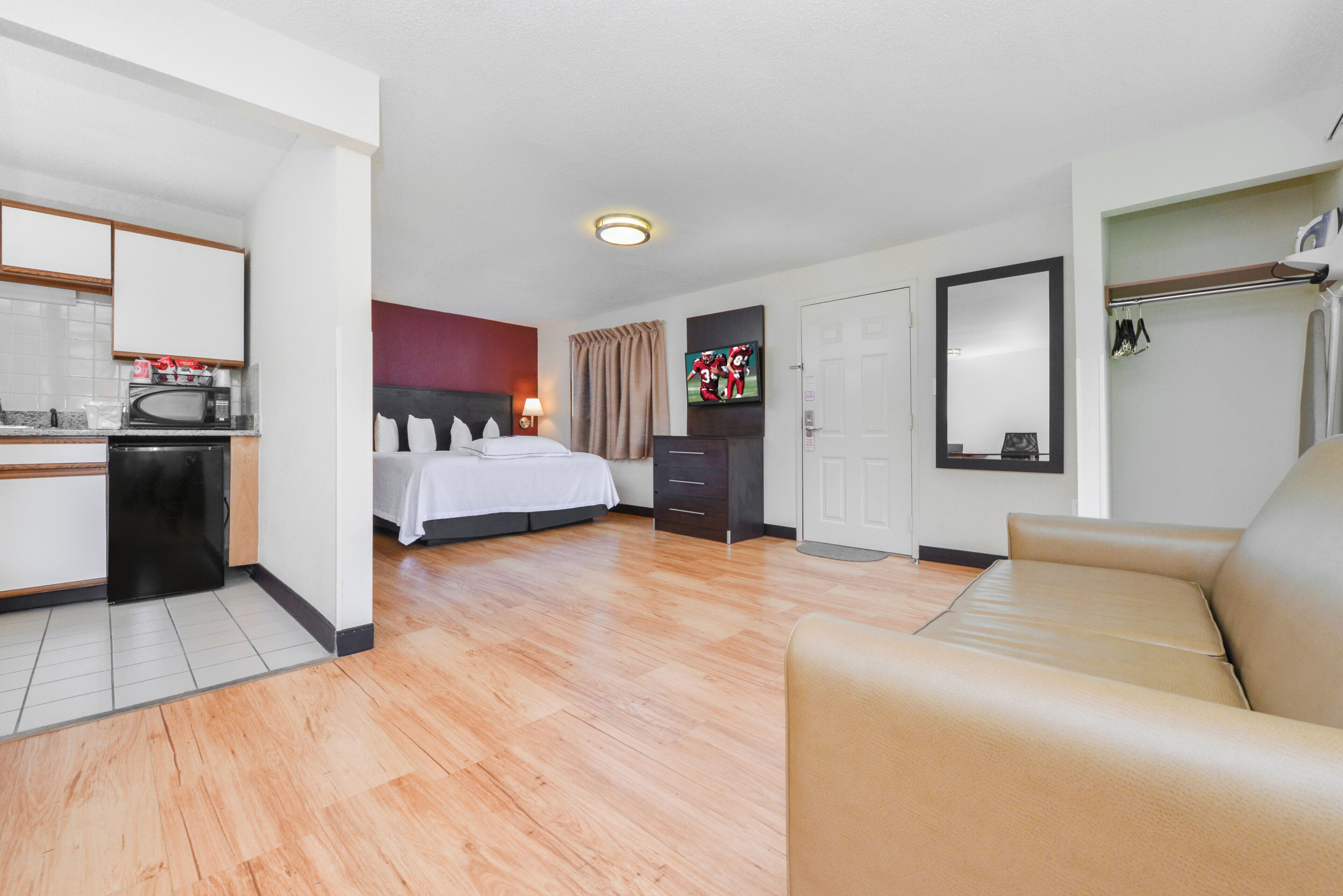 Une chambre d’hôtel comprenant un lit, un canapé, une télévision, une armoire et une kitchenette.