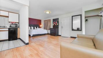 Une chambre d’hôtel comprenant un lit, un canapé, une télévision, une armoire et une kitchenette.