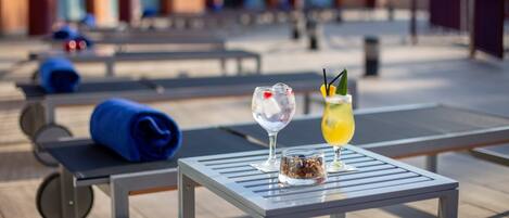 Una mesa con dos bebidas y una toalla enrollada en una terraza.