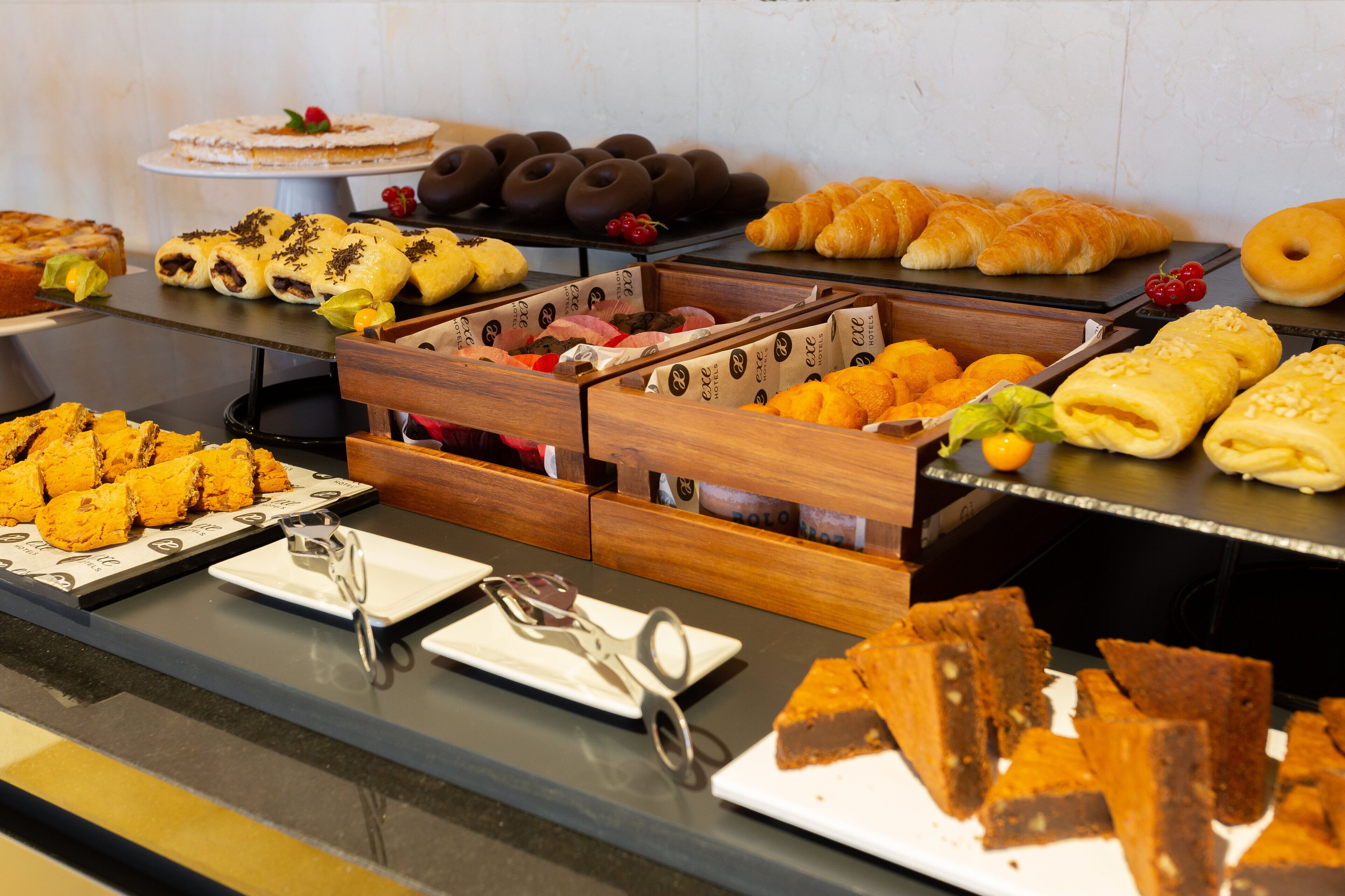 A buffet with various food items including pastries, cakes, and desserts.