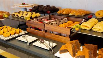 Un bufé con diversos alimentos, incluyendo pasteles, tartas y postres.
