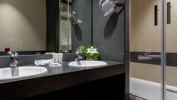 A modern bathroom with two sinks, a large mirror, and a glass shower enclosure.