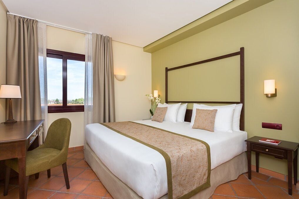 Een hotelkamer met een bed, een bureau, een stoel en een nachtkastje.