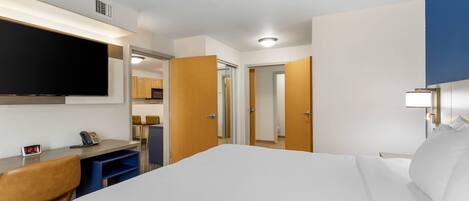 Habitación de hotel con cama, escritorio, silla, televisor y puerta que da a un baño.