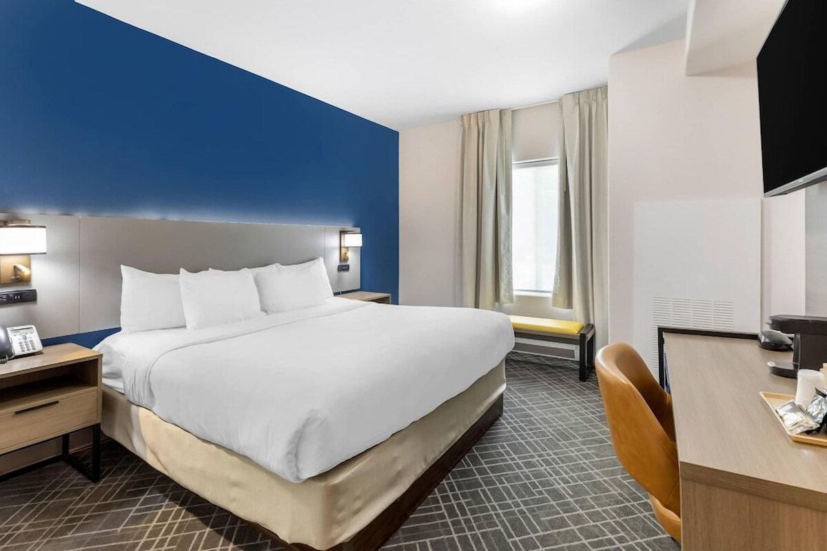 Una habitación de hotel con una cama grande, mesitas de noche, un escritorio y una silla.