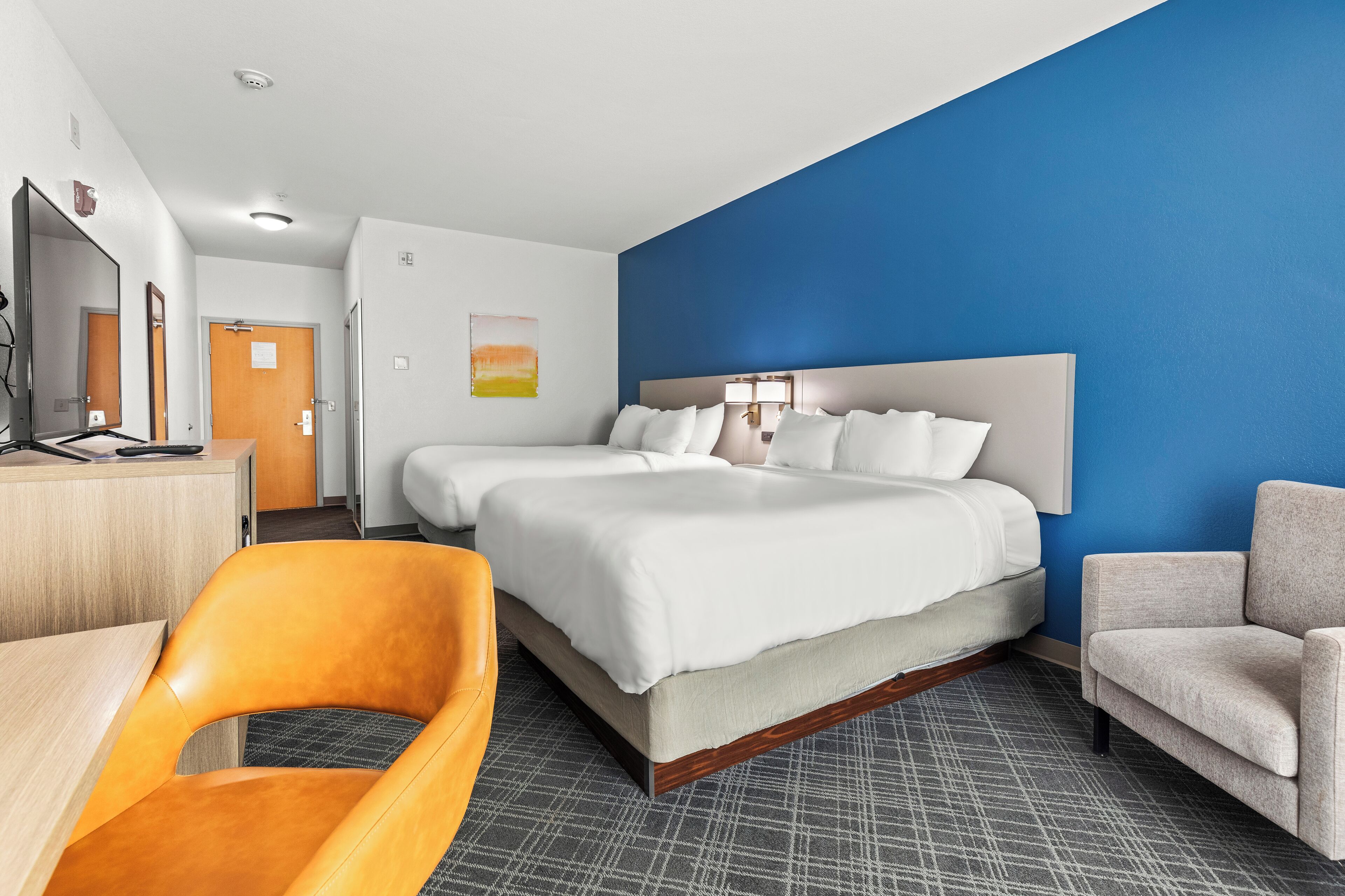 A hotel room with a large bed, two bedside tables, a desk, and a chair.