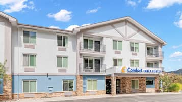 Un hotel de varios pisos con un letrero que dice 'Comfort Inn & Suites', balcones y fachada de piedra.