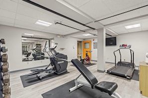 Un gimnasio con equipamiento de ejercicio, un espejo y una televisión.