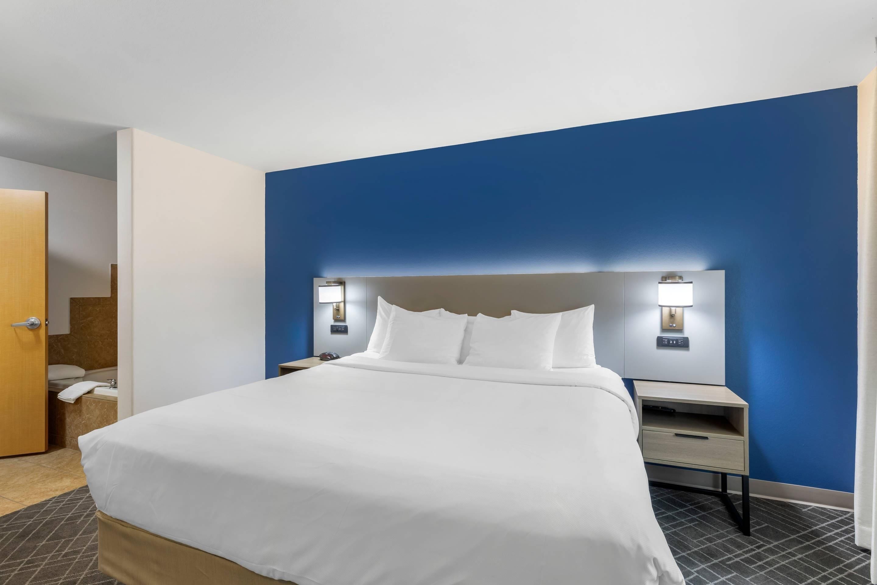 A hotel room with a bed, nightstands, a headboard, and a door.