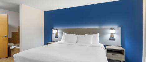 A hotel room with a bed, nightstands, a headboard, and a door.