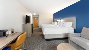 Habitación de hotel con cama, escritorio con computadora, silla, sofá y televisión.