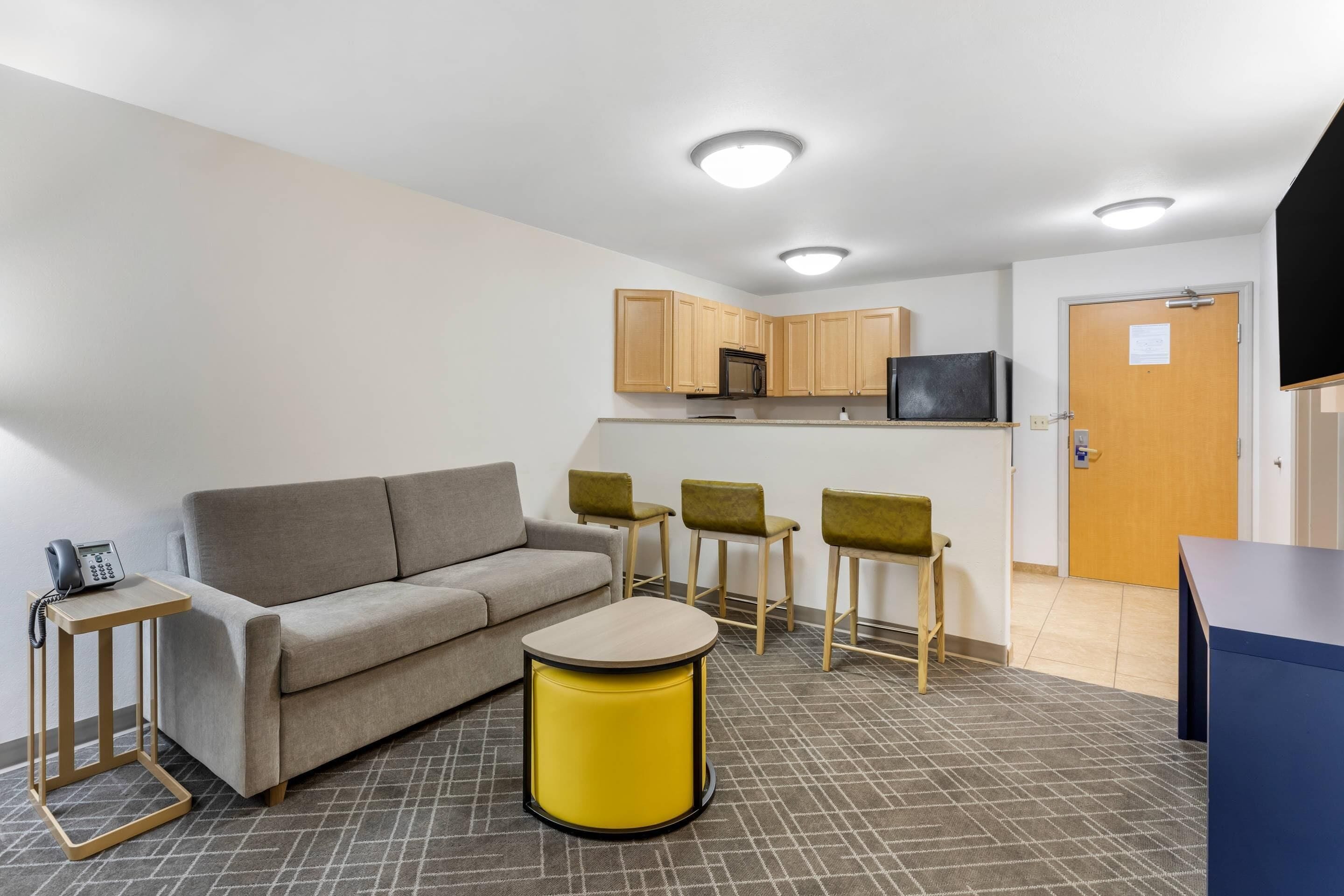 A modern living room with a sofa, a yellow coffee table, and a TV.