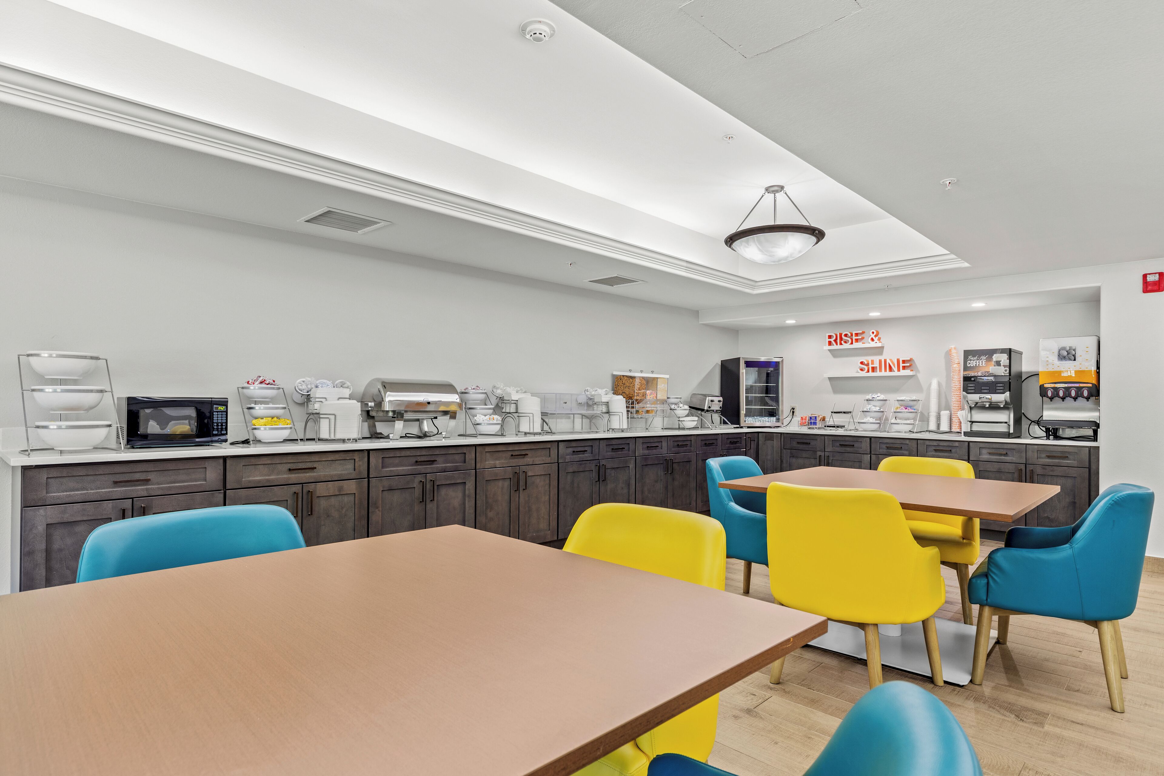 A modern kitchen with a central island, built-in appliances, and a dining area with colorful chairs.