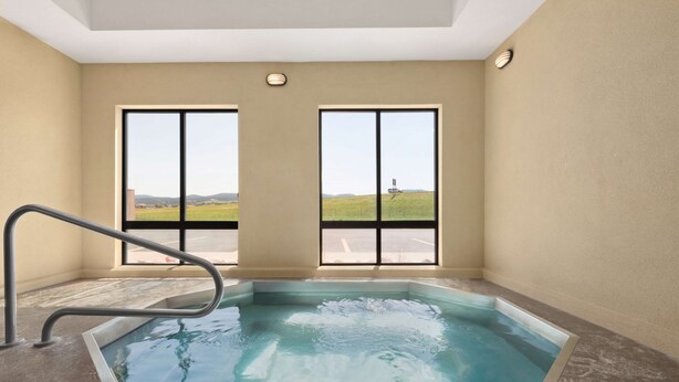 Un jacuzzi con vista a un campo a través de amplios ventanales.
