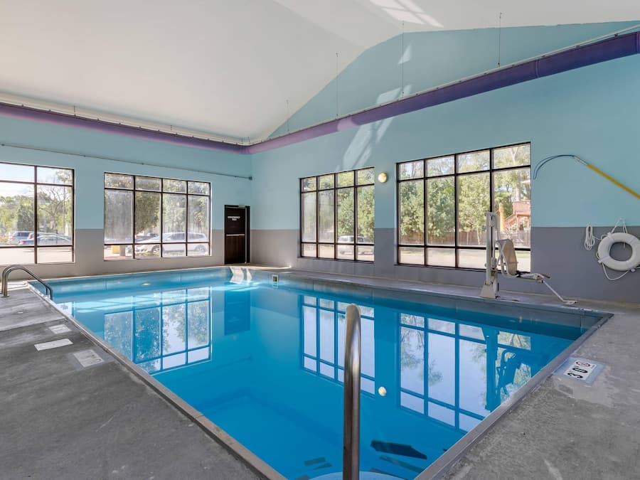 Una piscina interior con ventanales, una silla de salvavidas y un flotador en la pared.