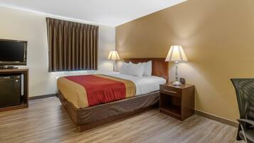 A hotel room with a bed, two bedside lamps, a TV, and a desk with a lamp.