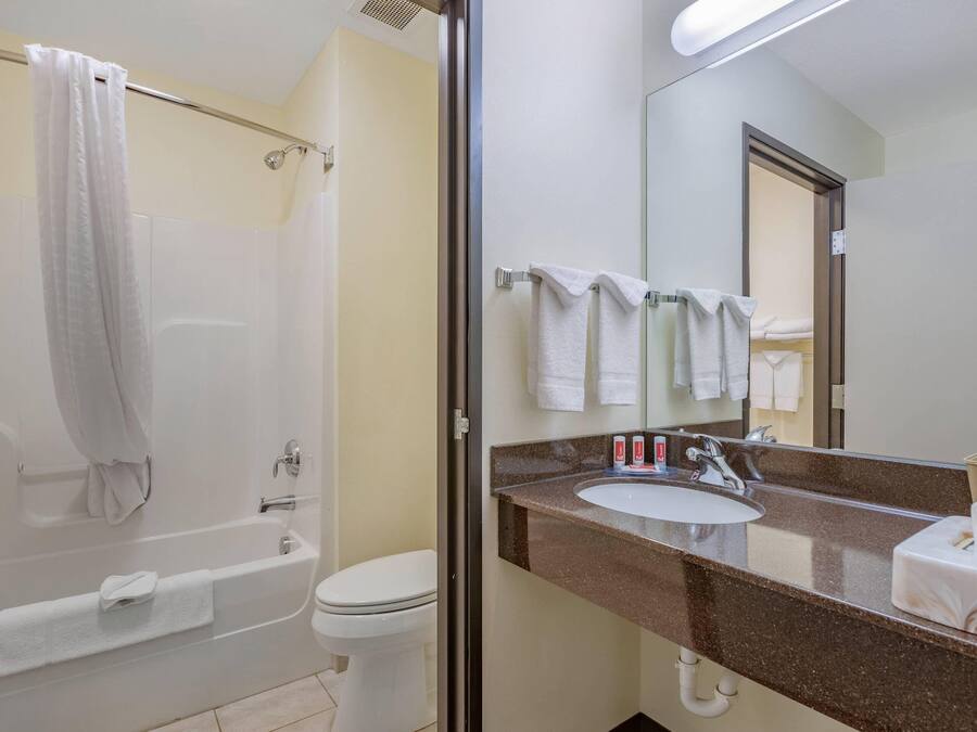 A bathroom with a bathtub, toilet, sink, and a large mirror.