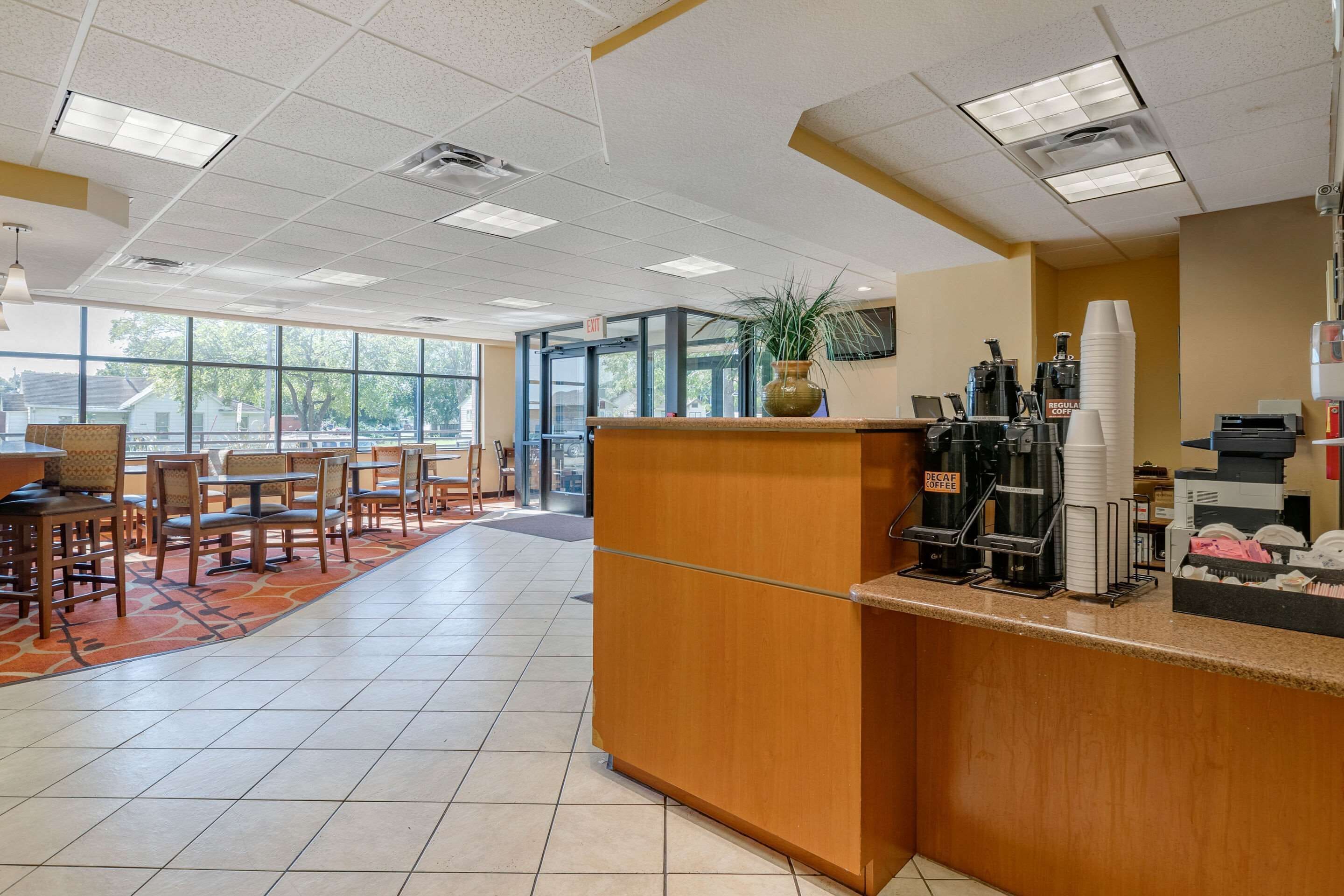 A clean, modern coffee shop with a wooden counter, seating area, and large windows.