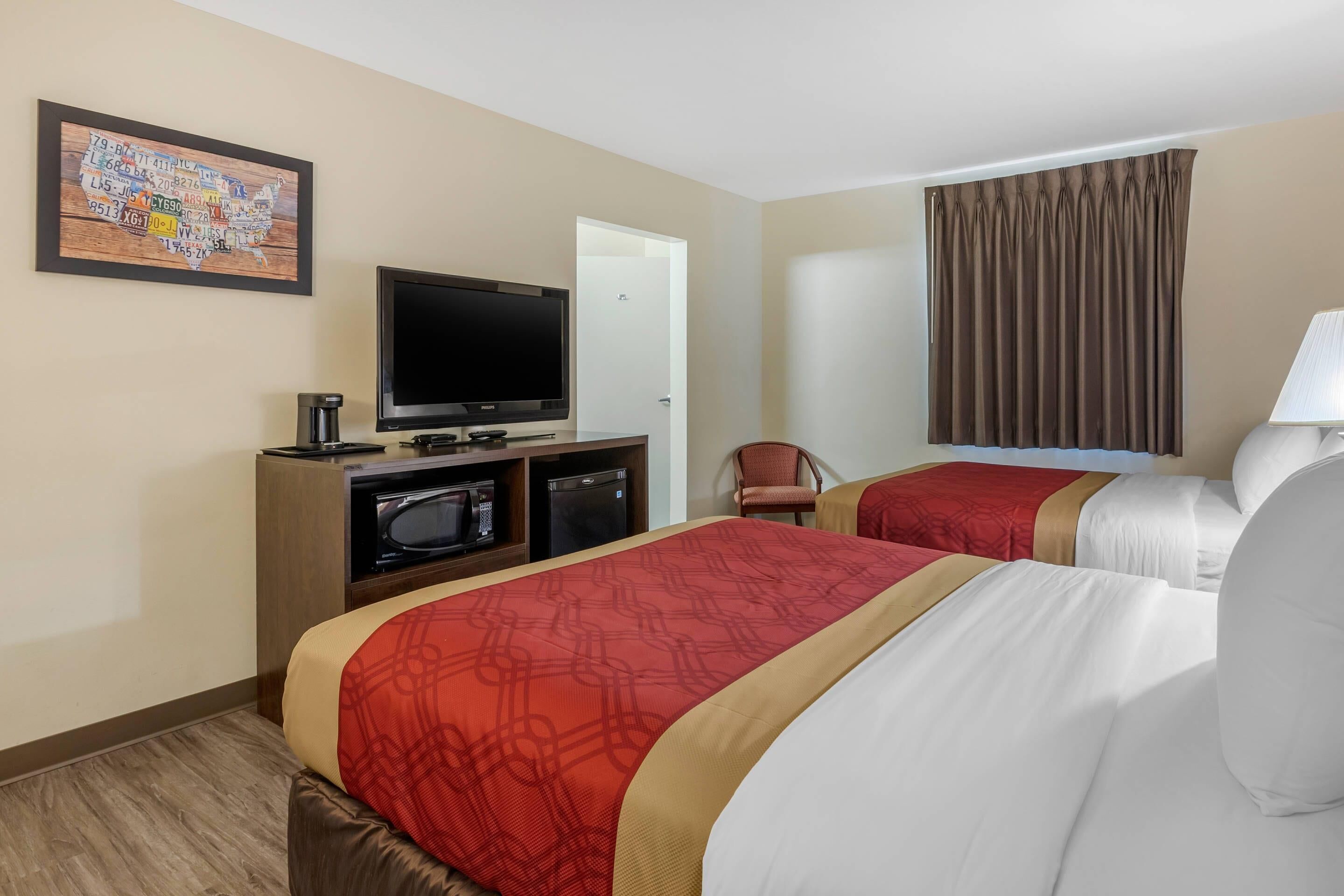 Una habitación de hotel con dos camas, televisión, microondas y cafetera.