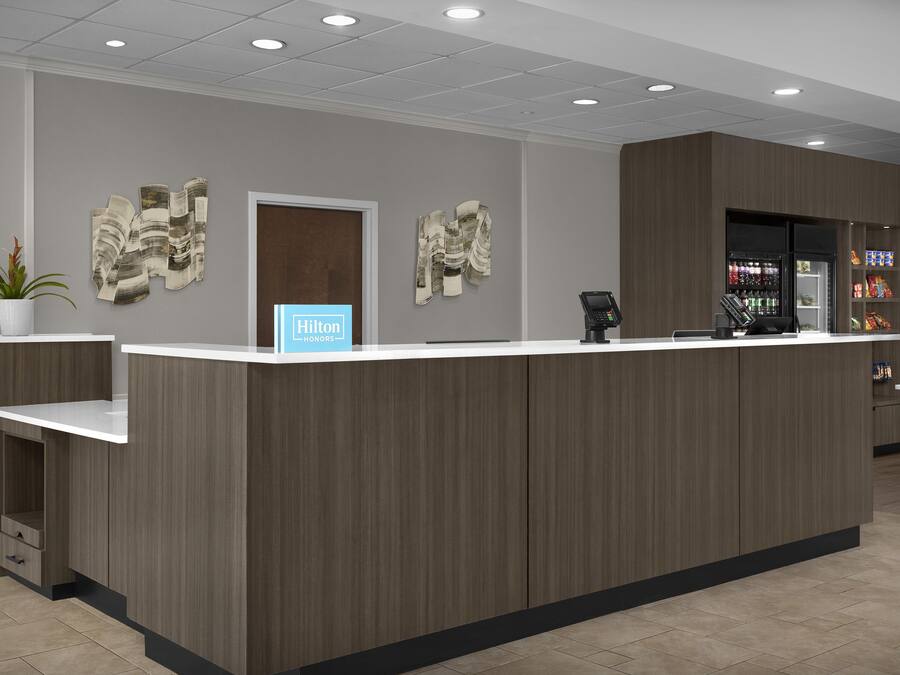 Una recepción de hotel con diseño moderno, una caja registradora y un dispensador de bebidas.