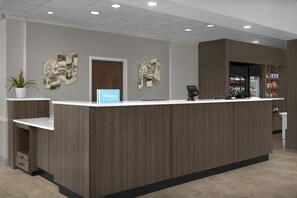 A hotel reception desk with a modern design, a cash register, and a beverage dispenser. - Hilton Garden Inn Macon / Mercer University (Macon)