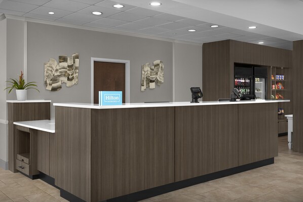 Una recepción de hotel con diseño moderno, una caja registradora y un dispensador de bebidas.