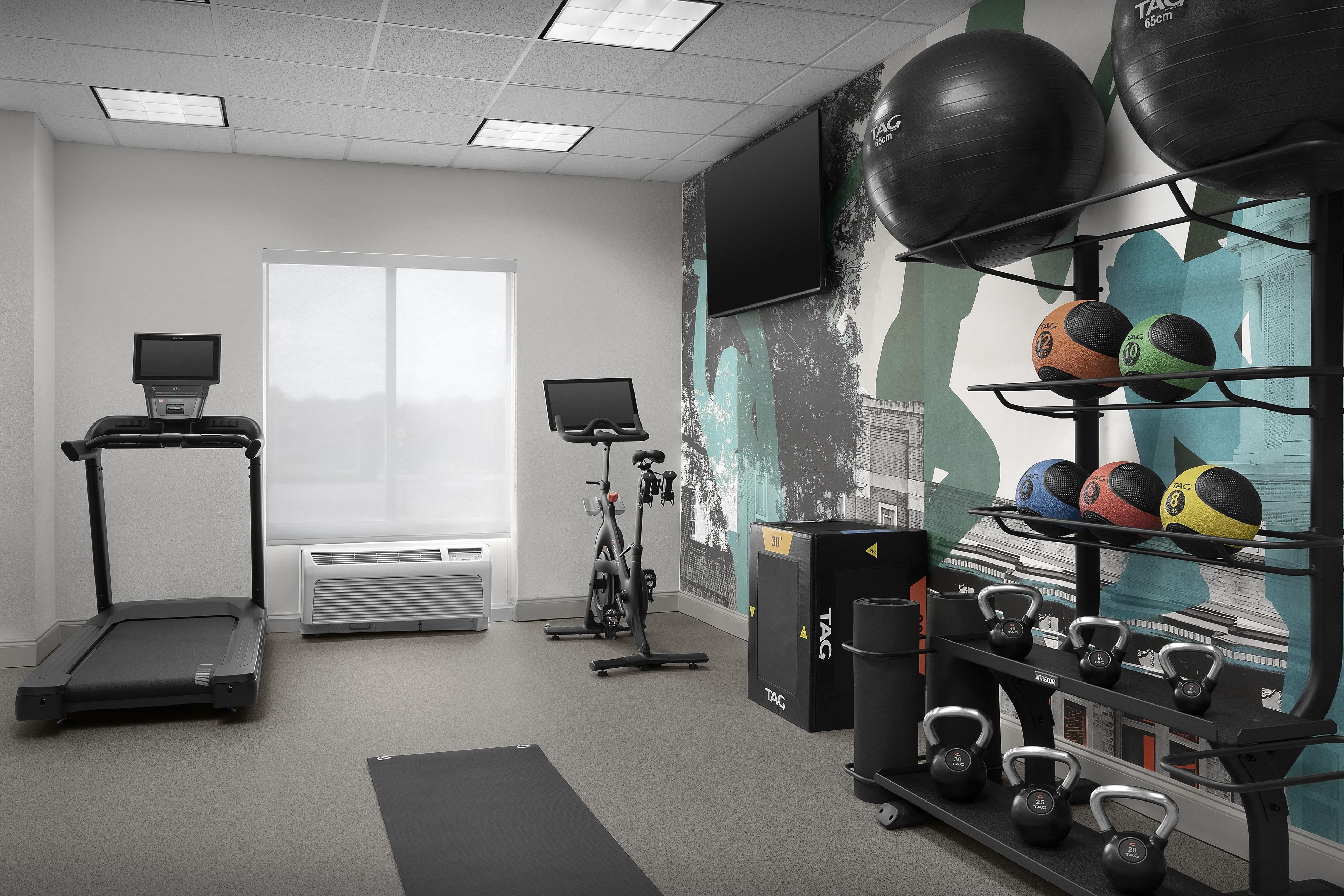 A gym with exercise equipment, treadmills, and a wall-mounted TV.