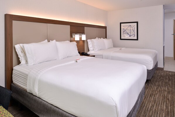 A hotel room with two beds, a headboard, a nightstand, a framed abstract artwork, and a carpeted floor.