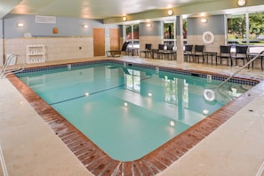 A swimming pool with a tiled edge, a changing room area, and a seating area with chairs and tables.