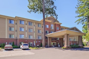 A multi-story hotel with a covered entrance and a parking lot.