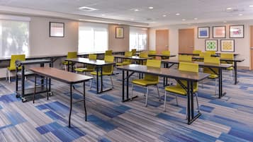 A conference room with multiple tables and chairs, carpeted flooring, and framed artwork on the walls.