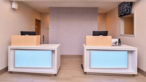A reception area with two reception desks, a wall-mounted television, and a door. - Holiday Inn Express & Suites Lacey – Olympia by IHG (Lacey)