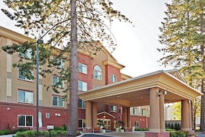 A multi-story hotel with a covered entrance, large windows, and a brick facade.