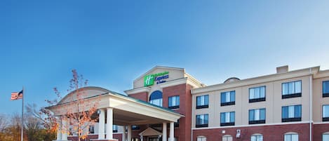 Un hotel Holiday Inn Express con entrada cubierta, varios pisos y un cielo despejado.